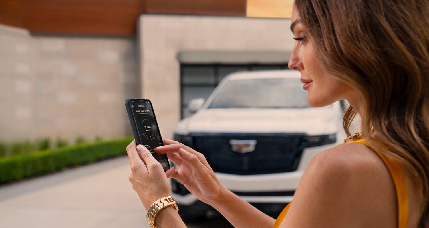 lady checking her mobile with a Cadillac vehicle background | O'Malley Cadillac in Wausau WI